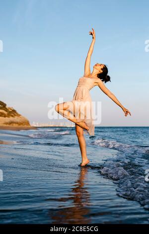 Zarte Ballerina tanzen am Strand bei Sonnenuntergang Stockfoto