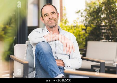 Entspannter Mann auf dem Stuhl im Hinterhof Stockfoto