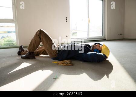 Bauarbeiter mit Händen hinter dem Kopf schlafen auf dem Boden in Haus im Bau Stockfoto