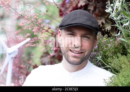 Lächelnder männlicher Unternehmer, der Windturbinenmodell von den Werken hält parken Stockfoto