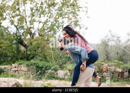 Glücklich Mann Huckepack Freundin beim Laufen im Freien Stockfoto