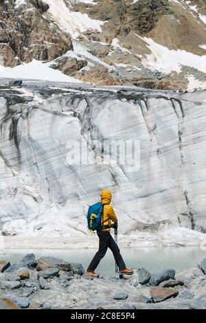 Reifer Mann, der auf Felsen steht und den schmelzenden Gletscher erkundet Stockfoto