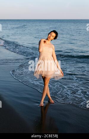 Zarte Ballerina tanzen am Strand bei Sonnenuntergang Stockfoto