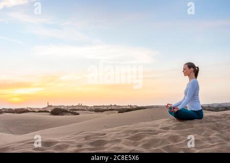 Frau praktiziert Yoga bei Sonnenuntergang in den Dünen, Gran Canaria, Spanien Stockfoto
