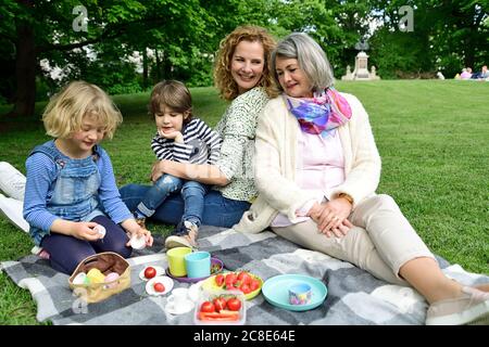 Glückliche Kinder genießen Picknick mit Mutter und Großmutter in der Öffentlichkeit parken Stockfoto