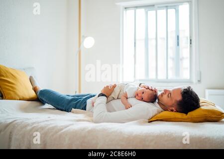 Niedlichen Baby Junge auf Vater im Schlafzimmer zu Hause liegen Stockfoto