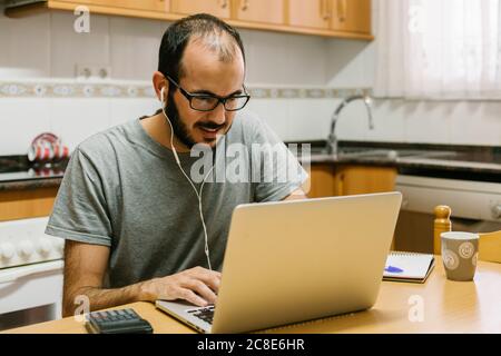 Man-Videokonferenzen auf einem Laptop, während man zu Hause arbeitet Stockfoto