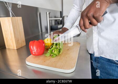 Crop-Ansicht von Mann schneiden Sellerie auf Küchentisch, Nahaufnahme Stockfoto