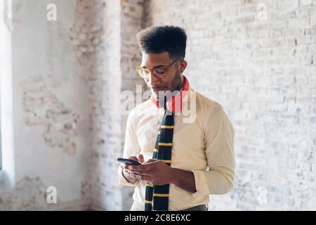 Stilvoller junger Mann mit Smartphone im Loft Stockfoto