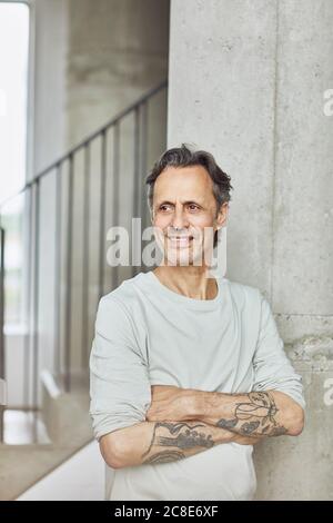 Lächelnder tätowiert älterer Mann in einer Loft-Wohnung Stockfoto