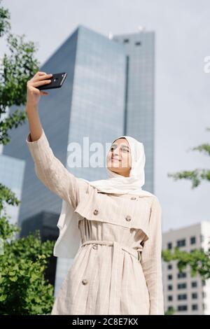 Muslimische Teenager-Mädchen, die Selfie durch Smartphone in der Stadt An sonnigen Tagen Stockfoto