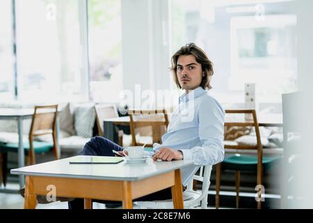 Serious Geschäftsmann mit Kaffee auf dem Tisch sitzen im Café Stockfoto