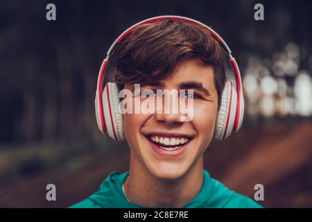 Teenager mit Kopfhörern im Regenmantel im Wald Stockfoto