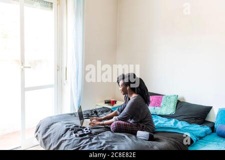 Junge Frau mit Laptop am Bett zu Hause Stockfoto