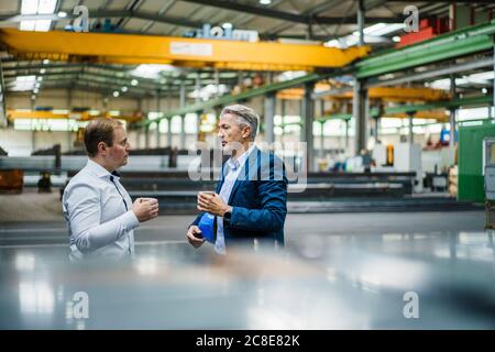 Zwei Geschäftsleute, die eine Kaffeepause in einer Fabrik machen Stockfoto