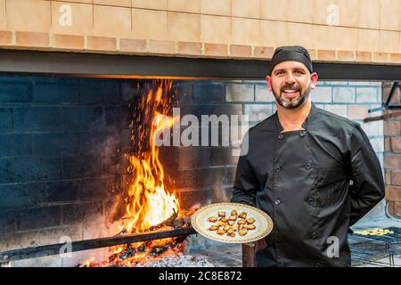 Traditionelle Küche im Restaurant ktischen, Koch zeigt Teller mit gegrillten Meeresfrüchten Stockfoto