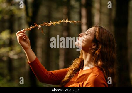 Nahaufnahme der schönen Frau mit geschlossenen Augen halten Pflanze in Wald Stockfoto