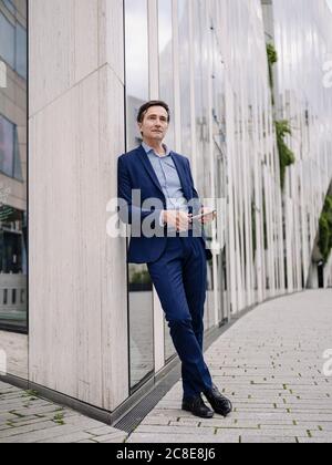 Serious reifen Geschäftsmann mit Tablet lehnt an ein Gebäude in Die Stadt Stockfoto