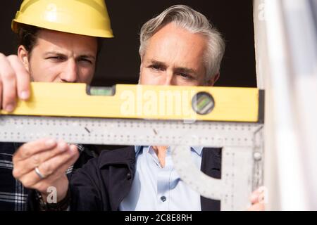 Nahaufnahme des Architekten und Bauarbeiter Messung Fensterrahmen gesehen Durch den Außenbereich Stockfoto