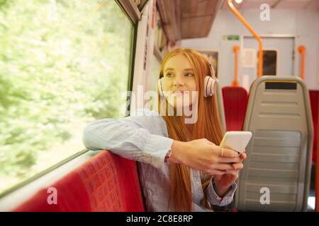 Schöne Frau, die Musik hört, während sie im Zug sitzt Stockfoto