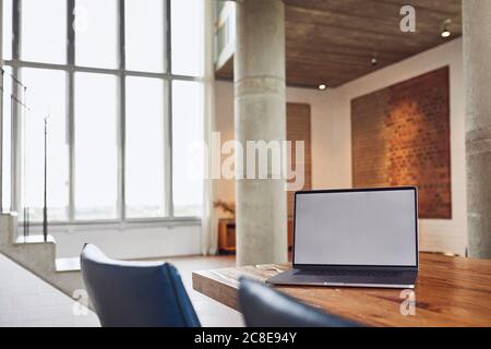 Laptop auf Holztisch in einer Loft-Wohnung Stockfoto