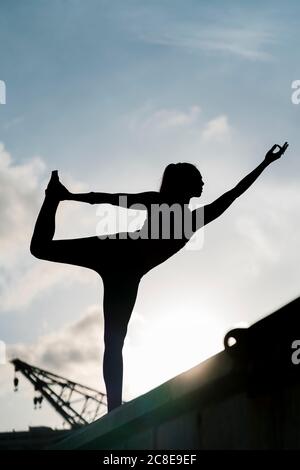 Silhouette Athletin üben Natarajasana auf Pier gegen Himmel Stockfoto