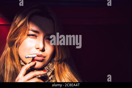 Nahaufnahme einer selbstbewussten Geschäftsfrau, die in der Stadt Zigarette raucht Stockfoto