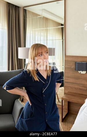 Durchdachtes Zimmermädchen mit den Händen auf der Hüfte im Hotelzimmer stehen Stockfoto