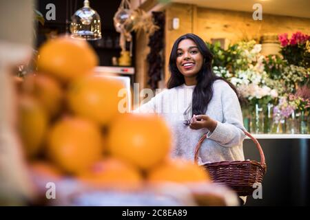 Glückliche junge Frau mit Korbkorb beim Einkaufen im Lebensmittelgeschäft Speichern Stockfoto