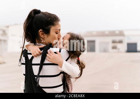 Mutter küsst Tochter auf Wange während sonnigen Tag Stockfoto