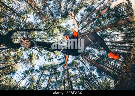 Reifer Mann springt gegen Bäume im Wald Stockfoto