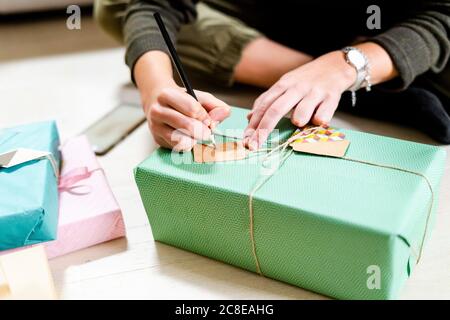 Die Hände der Frau schreiben auf dem Geschenk-Tag Stockfoto