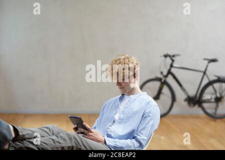 Junger Mann sitzt mit digitalen Tablet Stockfoto