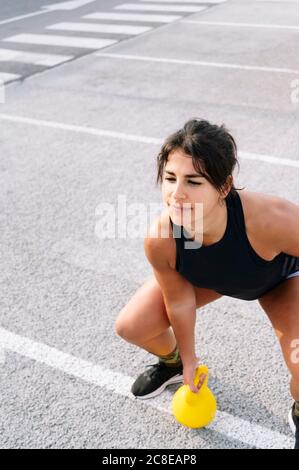 Selbstbewusste junge Frau beim Heben der Kettlebell auf der Straße Stockfoto