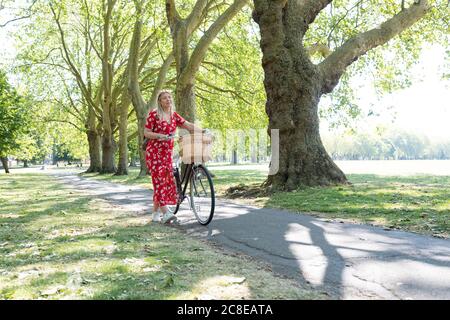Nachdenkliche Frau, die mit dem Fahrrad auf dem Fußweg im öffentlichen Park läuft Stockfoto
