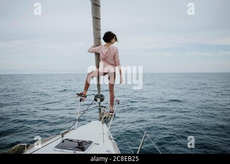 Weibliche Seemannin, die beim Stehen auf dem Bug der Ansicht ist Segelboot im Meer Stockfoto