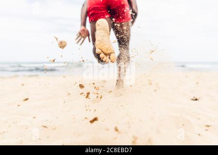 Athletischer Mann, der am Strand läuft Stockfoto