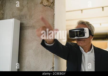 Reifer Geschäftsmann trägt VR-Brille, zeigt auf Distanz Stockfoto