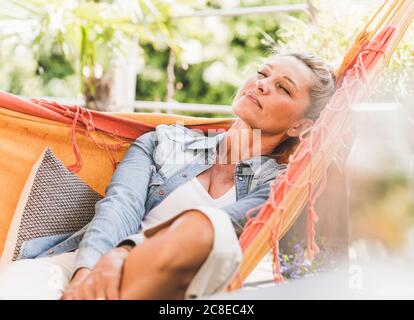 Porträt der reifen Frau mit geschlossenen Augen entspannend in der Hängematte Ein Stockfoto