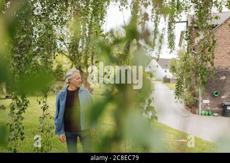 Älterer Mann, der in einem ländlichen Garten steht Stockfoto