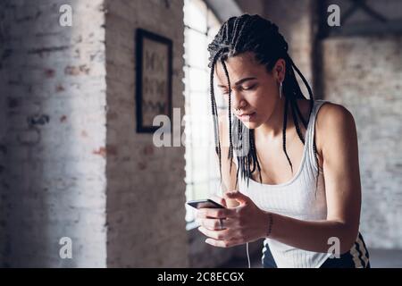 Stilvolle junge Frau mit Smartphone im Loft Stockfoto
