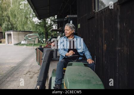 Senior man fährt Traktor mit Anhänger auf einem Bauernhof Stockfoto