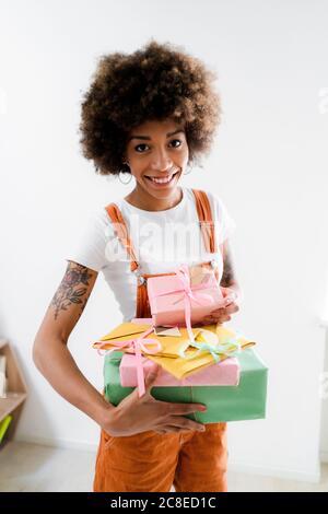 Porträt einer lächelnden jungen Frau mit eingewickelten Geschenken Stockfoto