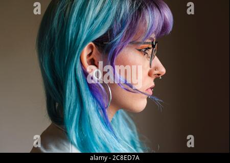Nahaufnahme einer nachdenklichen jungen Frau mit gefärbten Haaren und Piercings Gegen die Wand im alten Büro Stockfoto