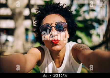 Nahaufnahme der stilvollen Frau trägt Sonnenbrille Puckering Lippen Stockfoto