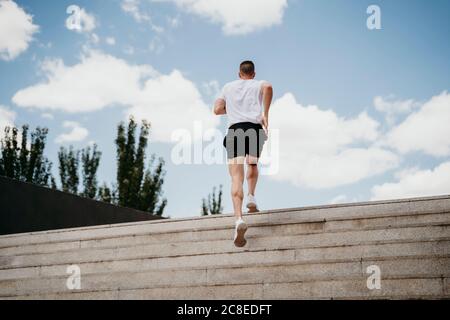 Männlicher Athlet, der die Treppe hinauf läuft Stockfoto