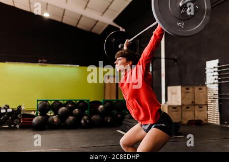 Weibliche Sportlerin, die im Fitnessstudio steht und Deadlift hebt Stockfoto