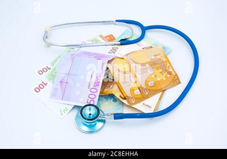Blaues Stethoskop ist um europäisches Bargeld Euro Geld isoliert auf weißem Hintergrund. Finanzgeschäftskonzept Stockfoto