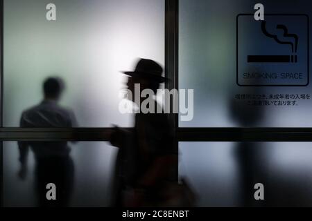 Ein Raucher in einem Raucherbereich eines Gebäudes in Roppongi, Tokio, Japan Stockfoto