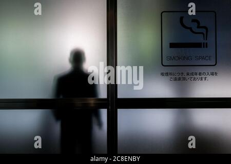 Ein Raucher in einem Raucherbereich eines Gebäudes in Roppongi, Tokio, Japan Stockfoto